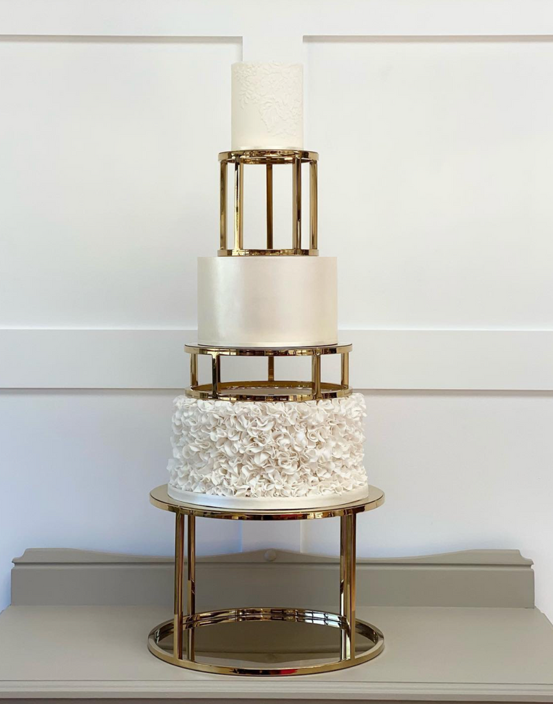 A white three tiered cake wih the layers separated by 6" & 10" Round Metallic Cake Spacers - Prop Options