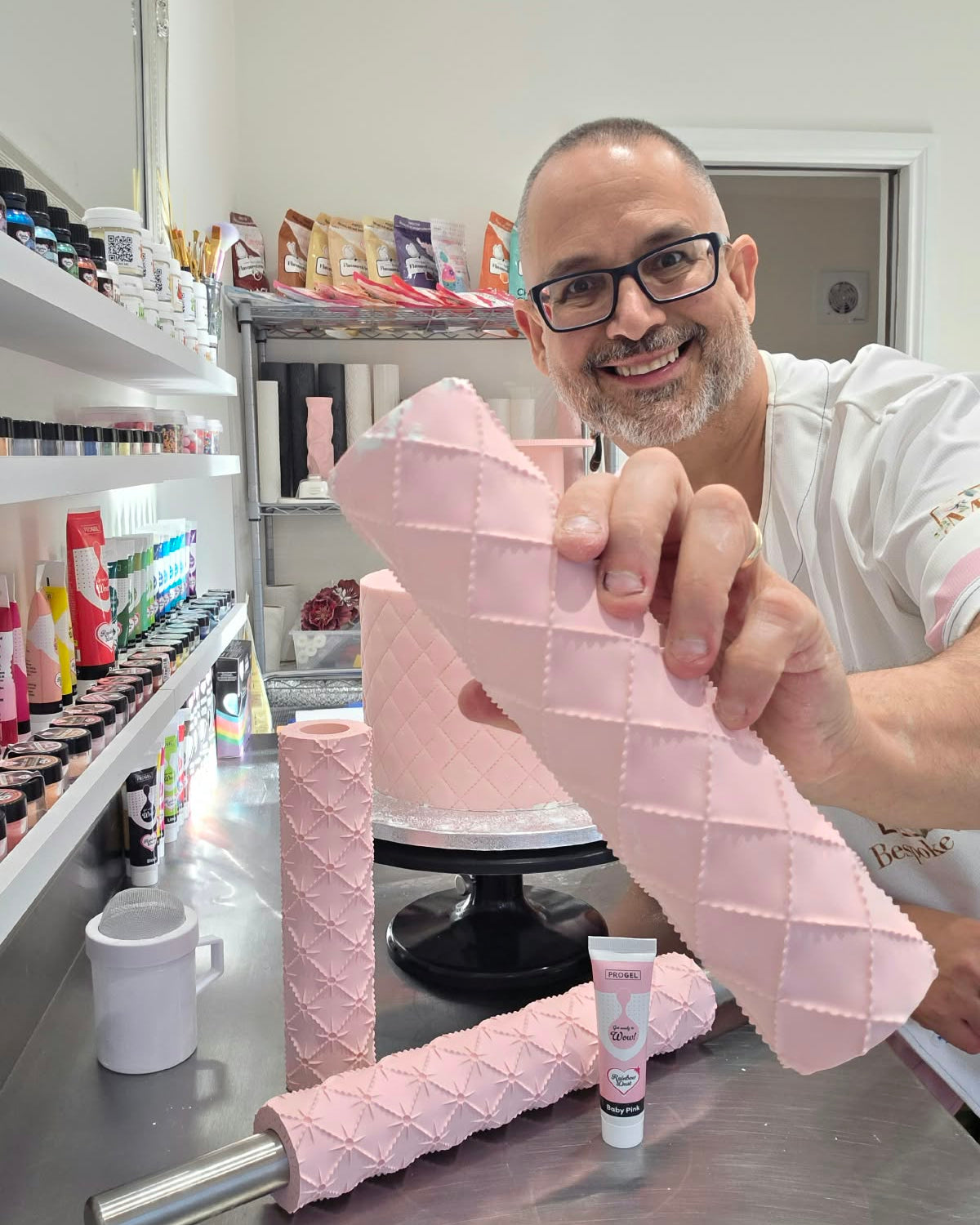 Victor Diaz holding a sheet of pink fondant rolled with the Quilted diamond pattern in front of a quilted cake - Prop Options