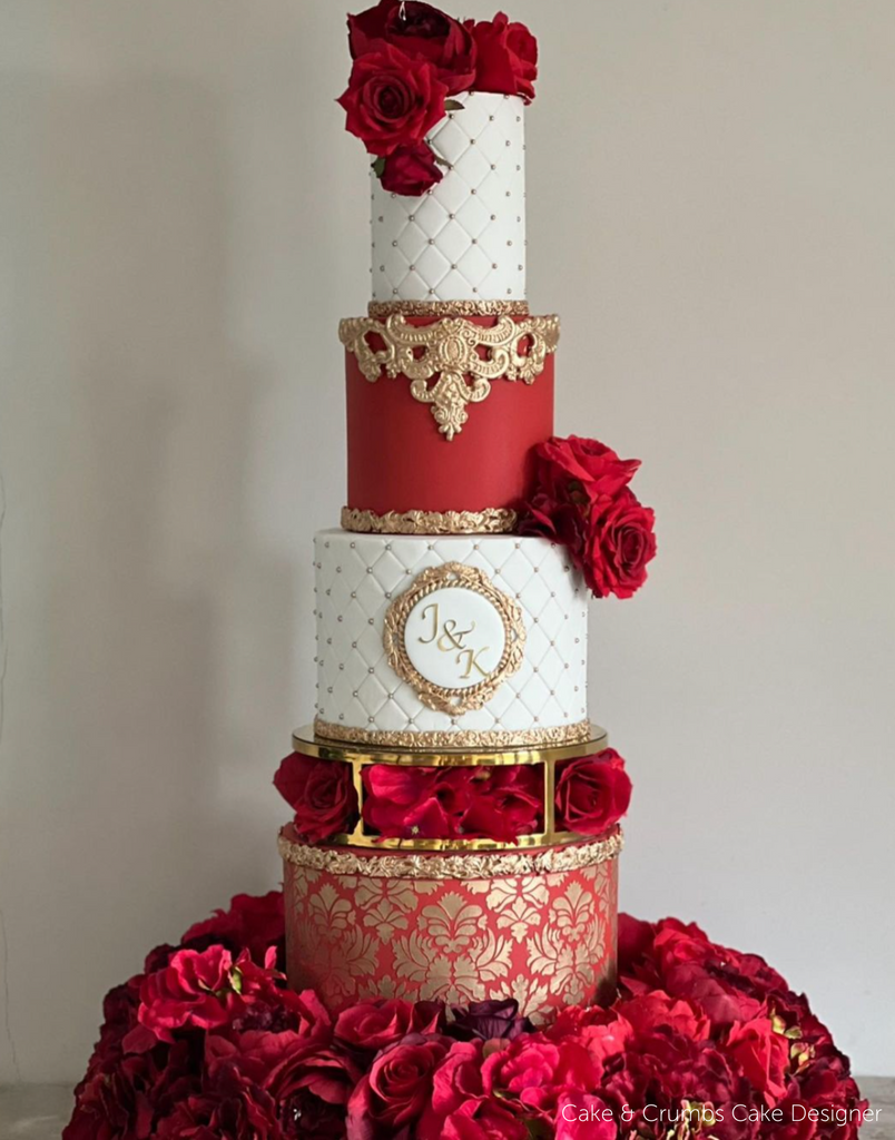 Elegant multitiered red and white cake with red roses and gold decorations and lettering being held up with a Gold 10" Round Metallic Cake Spacer - Prop Options