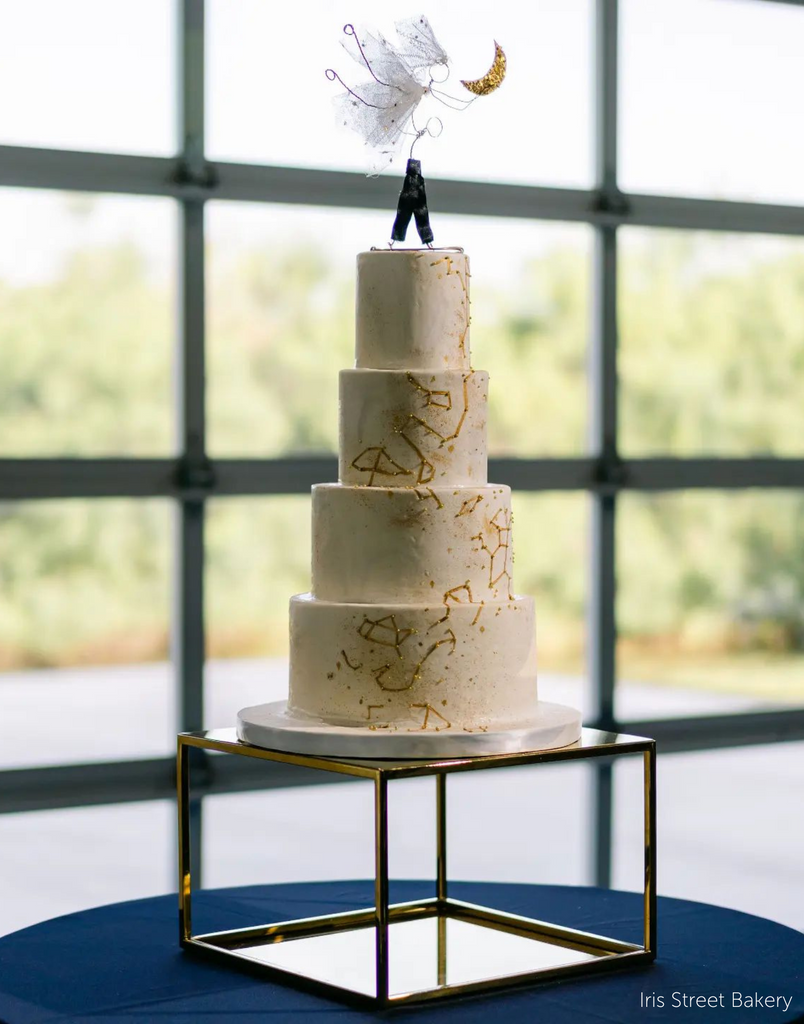 Gold Square Metallic Plinth holding up a multilayered white cake with a gold constellation design, on top of the cake is an angel made out of wire holding a gold moon - Prop Options