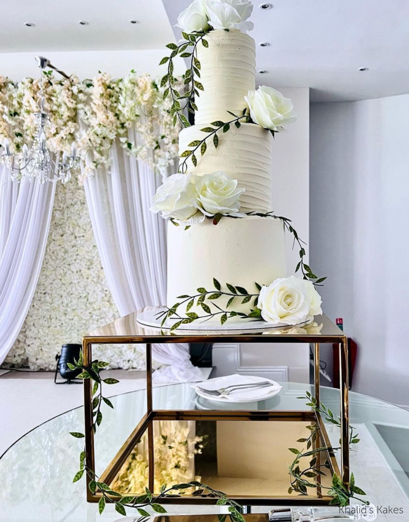 Gold Square Metallic Plinth holding up a tall white wedding cake covered in white roses - Prop Options