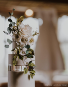 Close up of a white multitiered cake with white flowers on the top, each layer is separated by a 30mm Round Acrylic Cake Separator - Prop Options