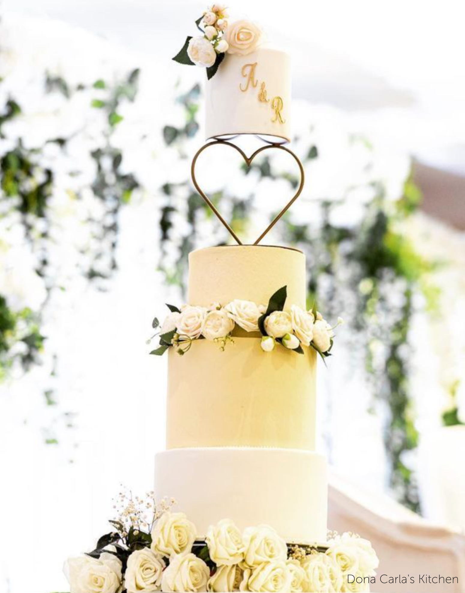 Cream and light yellow four tier cake with white roses, the top two layers are separated by a Heart Tier Separator - Prop Options