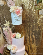 A plain white three tier cake with white and pink flowers, the middle is separated by a Hoop Tier Separator - Prop Options