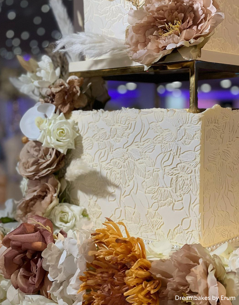 A close up of a white cake with floral decorations separated using a Rectangle Metallic Cake Spacer - Prop Options