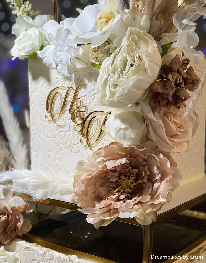 A close up of a white cake with light flower decorations sat on top of a Rectangle Metallic Cake Spacer - Prop Options