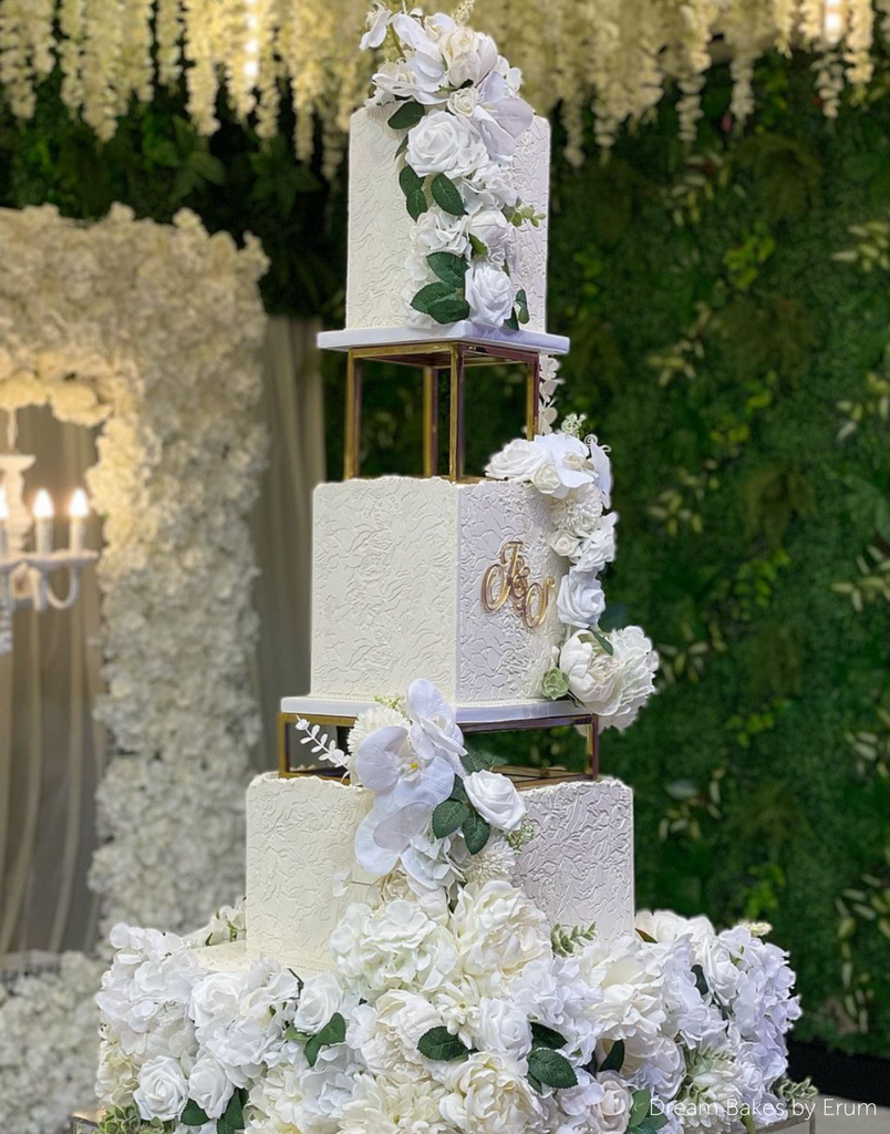 A white cake covered in white flowers separated by Square and Rectangle Metallic Cake Spacers - Prop Options