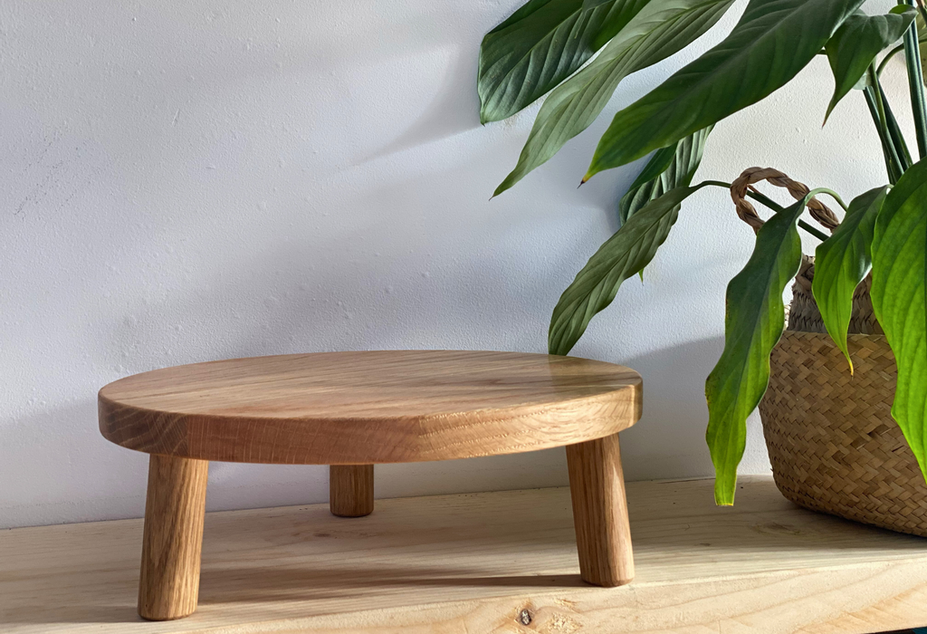 A Solid Oak Tripod Cake Stand stood next to a plant - Prop Options