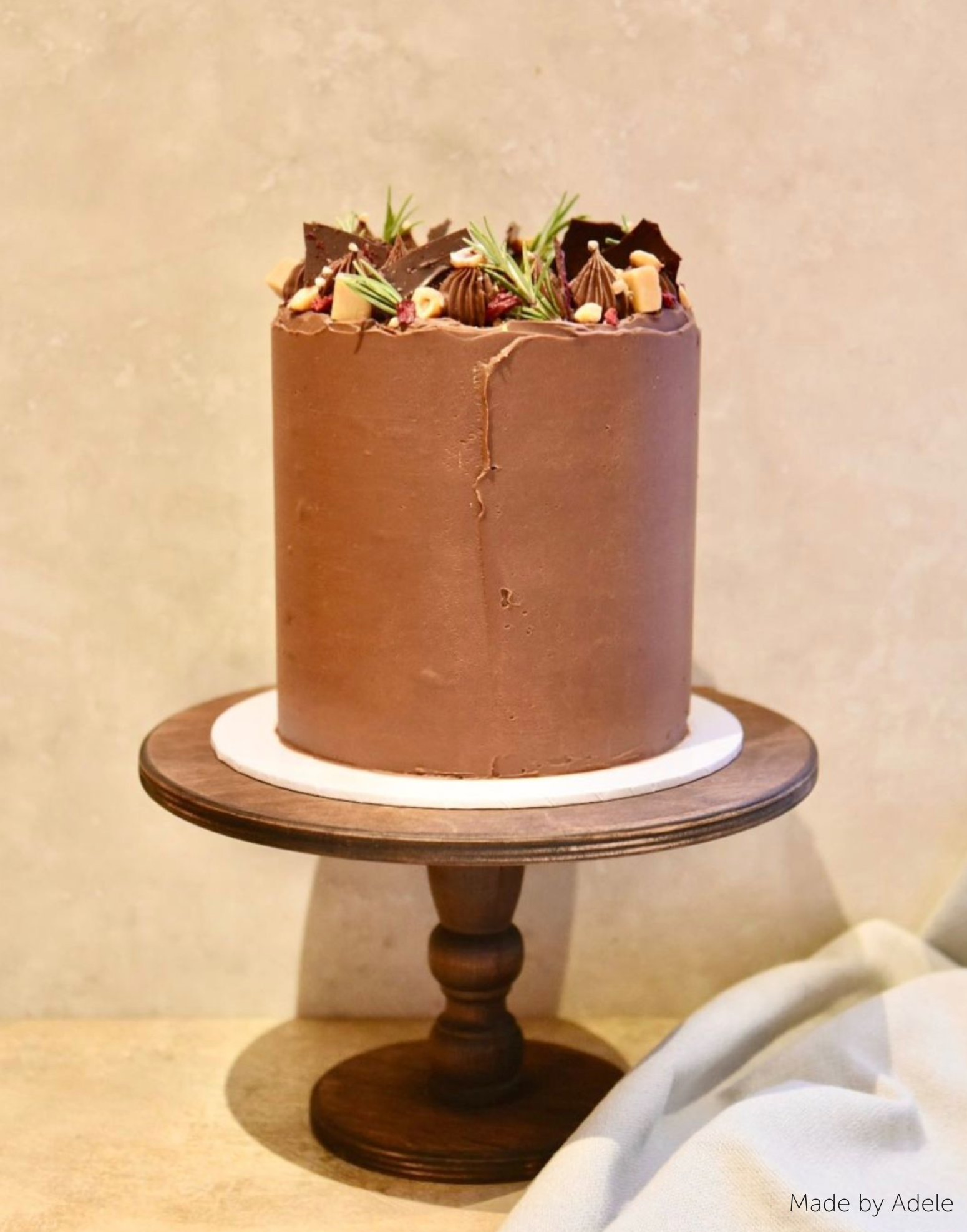 A brown cake with chocolate on the top stood on The Original Scandinavian Birch Cake Stand - Prop Options