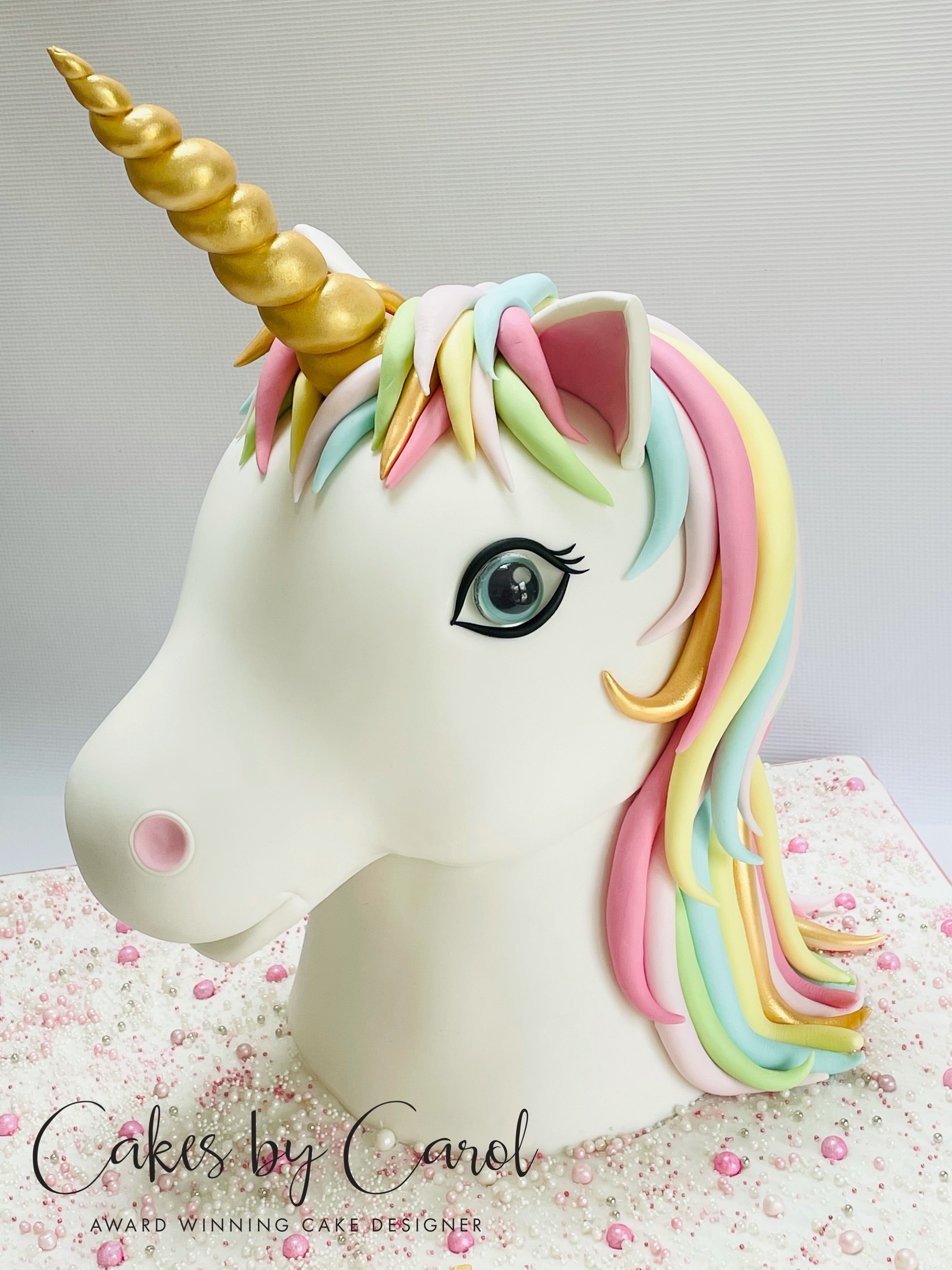 Unicorn cake with colorful mane and gold horn on a light background