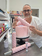 Victor Diaz holding the Quilted rolling pin pattern rolled in pink fondant beside a quilted cake, with the Quilted Pearl pins on the bench - Prop Options
