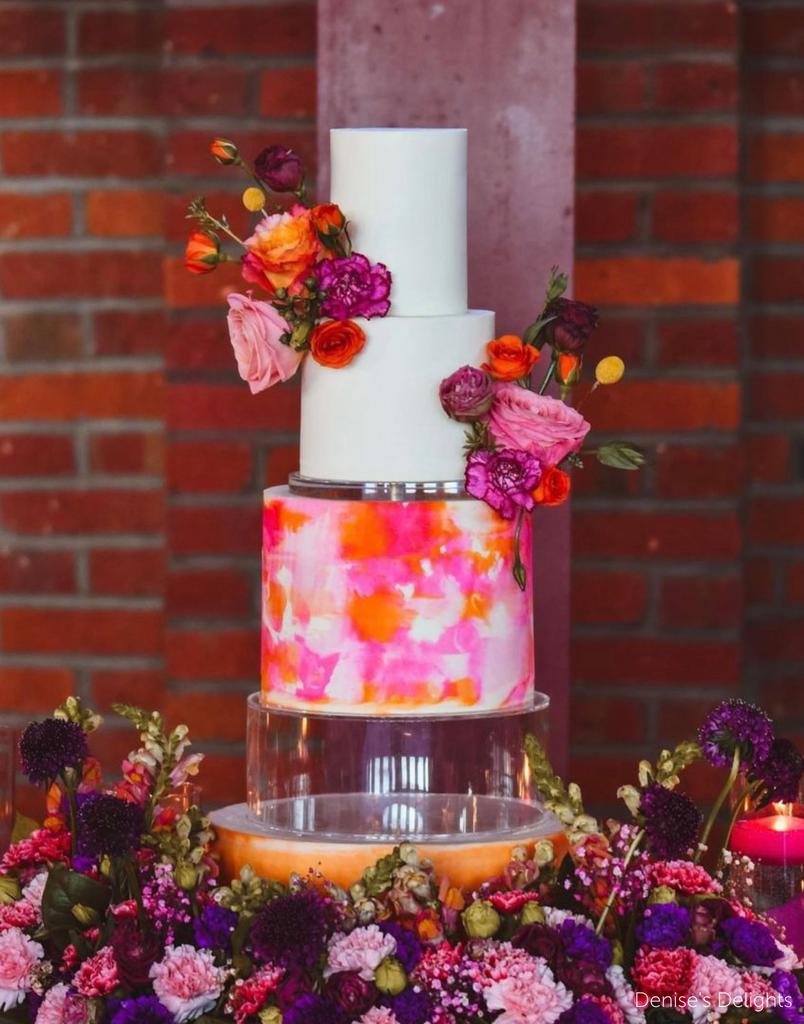 Three tier cake with plain white tiers and a marbled pink and orange bottom tier with matching flower decorations, the bottom and middle tier are separated by a 15mm Acrylic Cake Separator - Prop Options