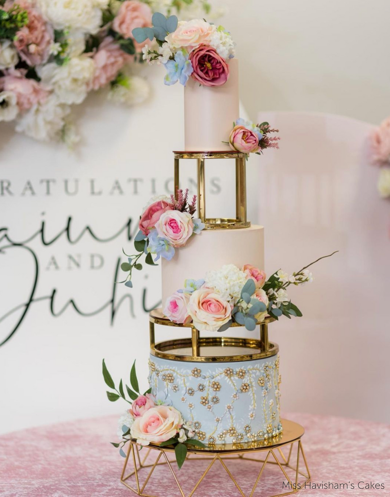 A Geometric Cake Stand holding a pastel blue and pink multitiered cake with pastel coloured flowers - Prop Options