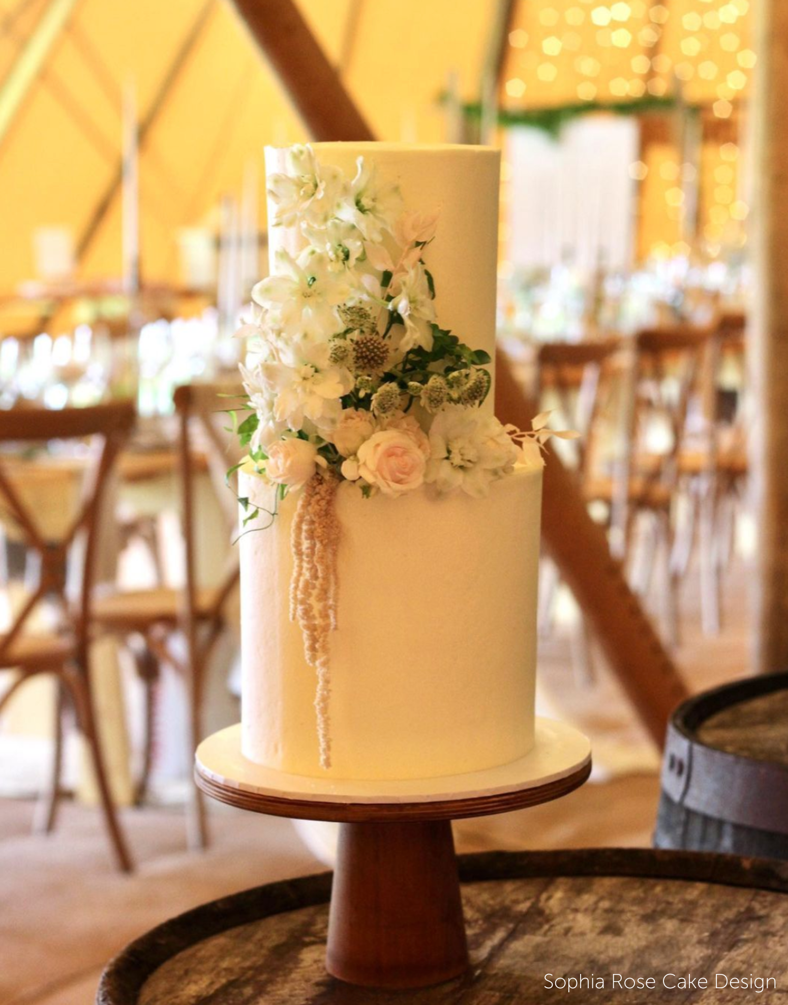 A white cake with pale flowers stood on The Scandinavian Cone Birch Cake Stand - Prop Options