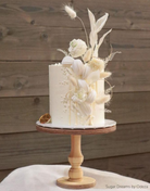 A white cake with light coloured florals stood on The Original Scandinavian Birch Cake Stand - Prop Options