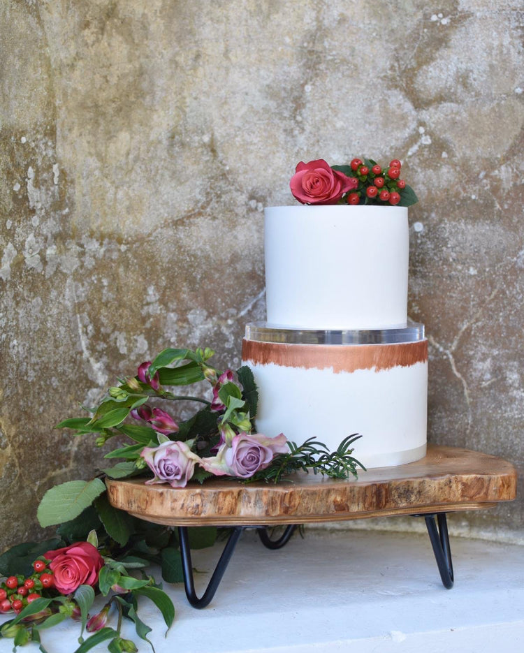 Ultra polished acrylic cake separator supporting cake and florals on solid wood log stand