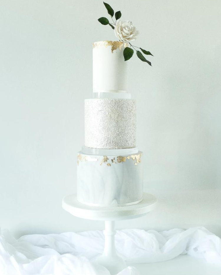 Ultra polished acrylic cake separator supporting stunning white tiered cake with rose